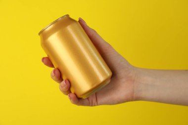 Sarı arka planda teneke kutusu olan kadın, yakın plan.