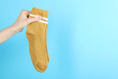 Açık mavi arka planda bir çift çorap giyen kadın, yakın plan. Metin için boşluk