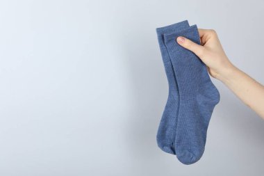 Açık gri arka planda bir çift çorap giyen kadın, yakın plan. Metin için boşluk