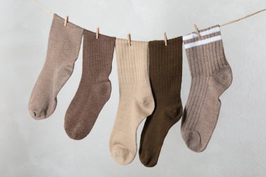 Açık gri arkaplanda çamaşır ipine asılı farklı çoraplar