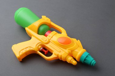 Gri arkaplanda parlak plastik su tabancası, yakın plan.