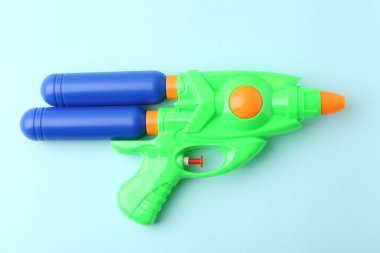 Açık mavi zemin üzerinde parlak plastik su tabancası, üst görünüm