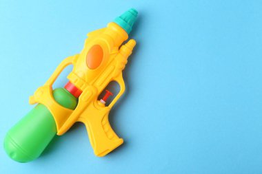 Açık mavi arka planda parlak plastik su tabancası, üst manzara. Metin için boşluk