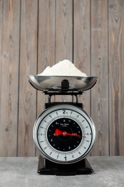 Retro mechanical kitchen scale with flour on grey table