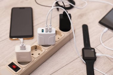 Kablolu USB adaptörleri ahşap zemindeki güç kablosu şarj cihazlarına takılı, yakın plan