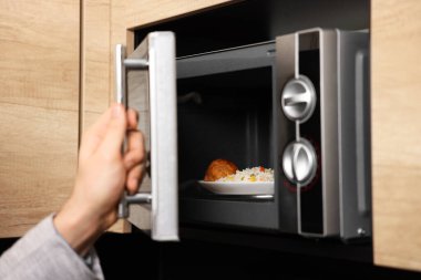 Yemek tabağını mikrodalgaya koyan adam, yakın plan.