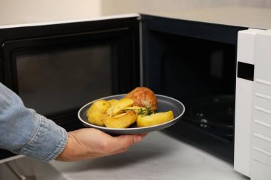 Yemek tabağını mikrodalgaya koyan adam, yakın plan.