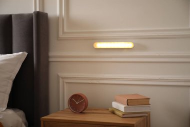 Kapalı bir odada beyaz duvarda parıldayan modern LED lamba.