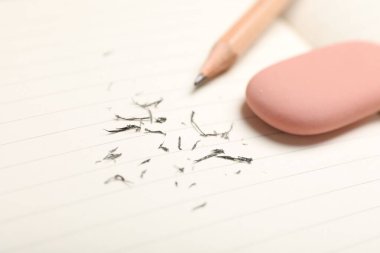 Eraser, pencil and scraps on lined notebook sheet, closeup. Space for text