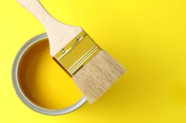 Sarı arka planda parlak boya ve fırça kutusu, üst manzara. Metin için boşluk