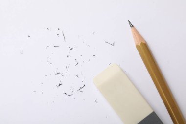 Eraser, pencil and scraps on white background, flat lay