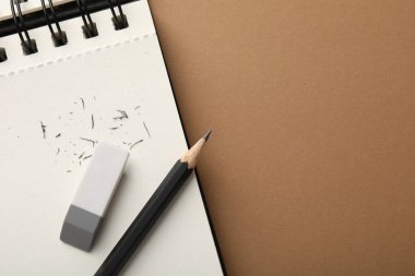 Silgi, kalem, kırıntılar ve kahverengi arka planda defter, üst manzara. Metin için boşluk