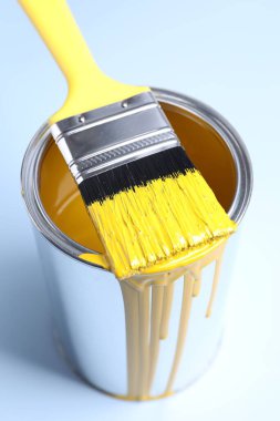Açık arkaplanda sarı boya ve fırça kutusu, yakın plan.