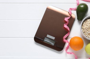 Elektronik mutfak ölçeği, mezura ve beyaz ahşap masa üzerindeki ürünler, düz yatak. Metin için boşluk