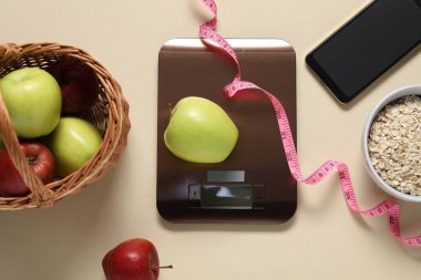 Elektronik mutfak ölçeği, mezura, akıllı telefon ve bej masadaki ürünler, düz yatak. Diyet