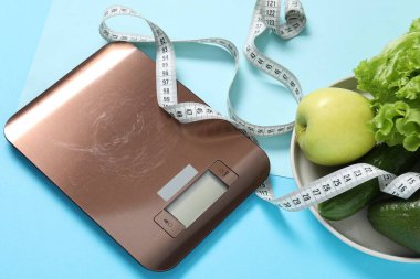 Elektronik mutfak ölçeği, ölçüm bandı ve açık mavi arka plandaki ürünler. Diyet