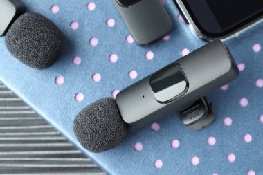 Lavalier mikrofonlar, kablosuz alıcısı olan akıllı telefon ve masadaki defter, üst görünüm.