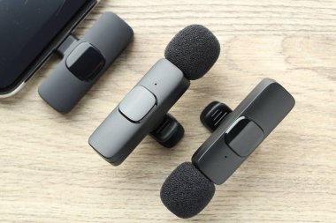 Lavalier mikrofonlar ve ahşap masada kablosuz alıcısı olan akıllı telefon.