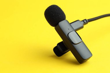 Sarı arka planda USB şarj kablosu olan Lavalier mikrofonu, yakın plan. Metin için boşluk