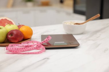 Mutfak pulları, meyveler, yulaf ezmesi ve beyaz mermer masa üzerindeki mezura, yakın plan.