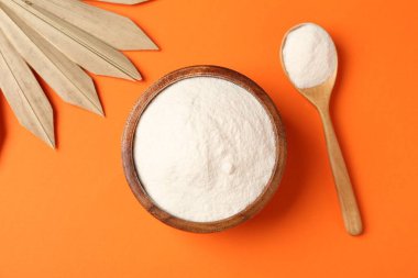 Kasede kolajen tozu, turuncu arka planda kaşık ve kuru palmiye yaprağı.