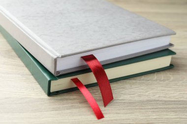 Açık ahşap masa üzerinde kırmızı kurdele yer imleri olan kitaplar, yakın plan