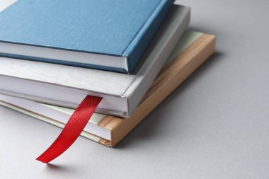 Açık gri masadaki renkli olanlar arasında kırmızı kurdele yer imi olan kitap, yakın plan