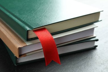 Kırmızı kurdele yer imi ve gri desenli masa üzerindeki renkli kitap, yakın plan.