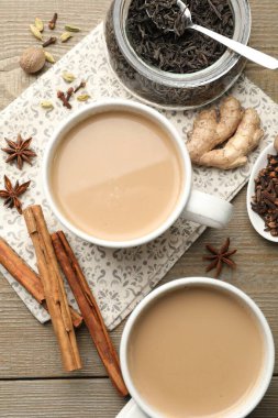 Fincanlarda Aromatik Masala çayı, ahşap masada kuru yapraklar ve baharatlar.