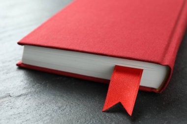 Koyu desenli masa üzerinde kırmızı kurdele yer imi olan kitap, yakın plan.