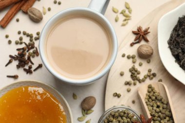Aromatik Masala çayı bardakta, baharatlar, kuru yapraklar ve bal açık gri masada, düz yerde.