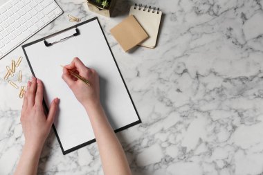 Beyaz mermer masadaki panoya yazı yazan kadın, üst manzara. Metin için boşluk