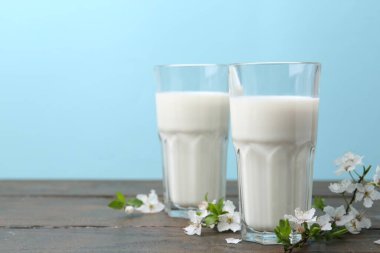 Taze süt ve çiçekler beyaz masada açık mavi arka planda. Metin için boşluk