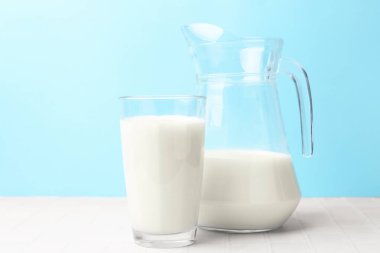 Açık mavi arka planda beyaz masada taze süt