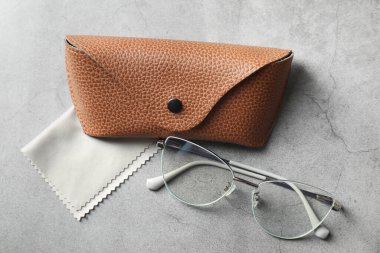 Şık gözlüklü bir çanta ve gri masada temiz bir bez.