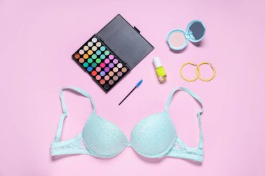 Pembe arka planda dantel sutyen ve kozmetik ürünlerle düz konum