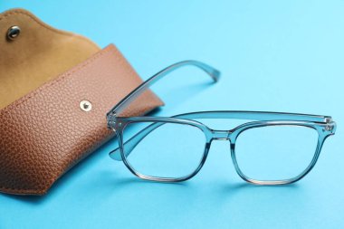 Açık mavi arka planda şık gözlüklü çanta, yakın plan