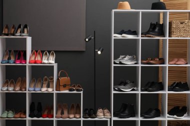 Ayakkabı deposu. Gri duvarın yanında farklı ayakkabı ve aksesuarlarla raf ünitesi.