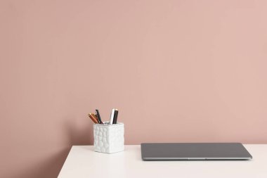 Laptop ve beyaz ofis masasındaki farklı kırtasiye malzemesi koyu bej arka planda