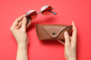 Güneş gözlüklü kadın ve kırmızı arka planda çanta, üst görünüm