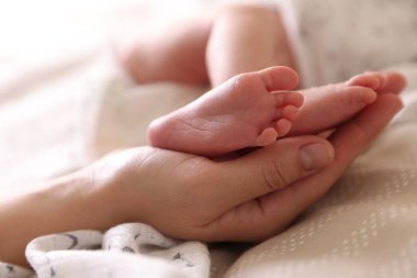 Anne, küçük bebeği evde, yatağında, yakın plan.