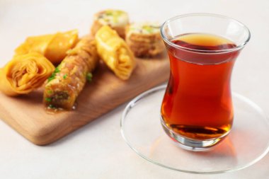 Geleneksel cam fincanda Türk çayı ve beyaz masada taze baklava, yakın plan.