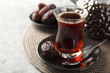 Geleneksel cam fincanda Türk çayı ve açık gri masada tarihler, yakın plan. Metin için boşluk