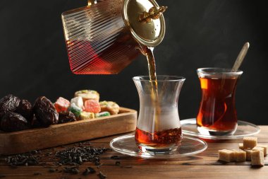 Tahta masada cam fincana Türk çayı dökülüyor, yakın plan.