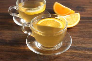 Ahşap masada portakal ve limonlu Aromatik meyve çayı, yakın plan.