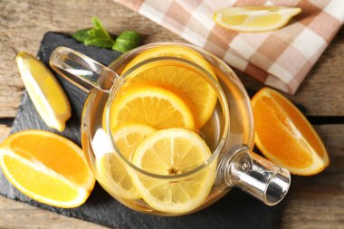 Cam çaydanlık aromalı meyve çayı, portakal, limon ve nane, ahşap masa, düz uzanmış.
