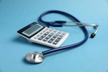 Açık mavi arkaplanda stetoskop ve hesap makinesi, yakın plan