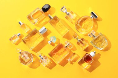 Sarı arka planda çeşitli parfüm şişeleri, düz yatıyordu.