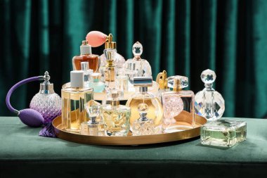 Deniz mavisi perdelerin yanındaki yeşil puf üzerinde farklı lüks parfümler.