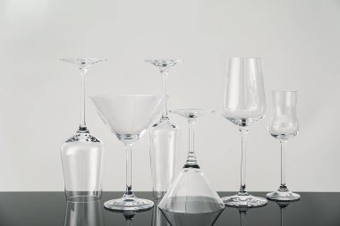 Gri arkaplana karşı ayna yüzeyinde birçok boş bardak